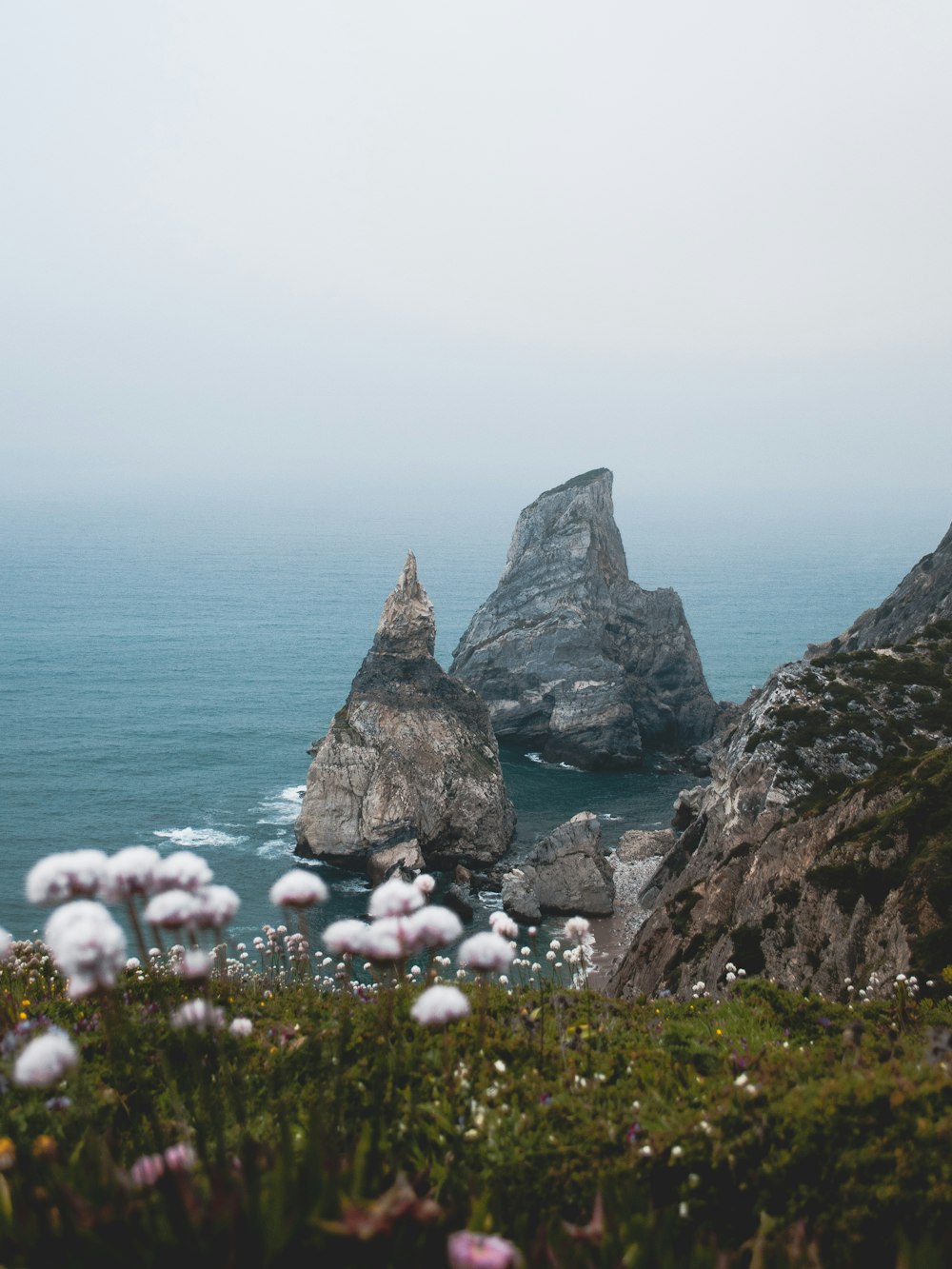 gray and brown rocks with body of water under cloudy sky during daytime