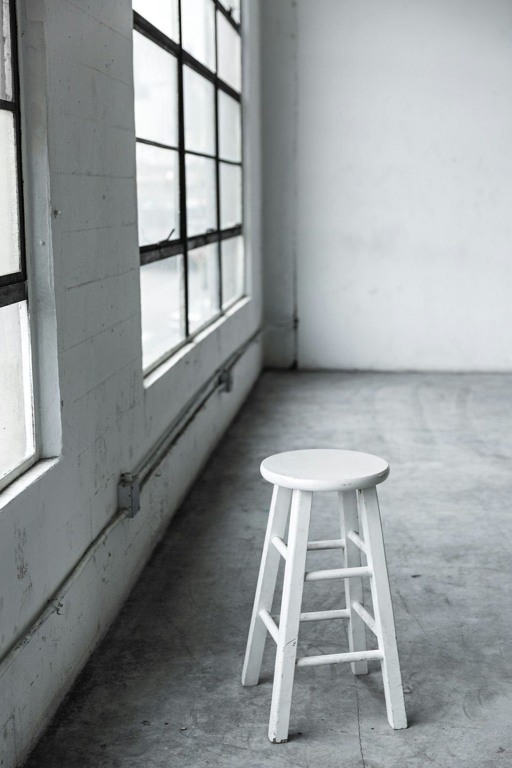 Tabouret rond en bois blanc près de la fenêtre fermée