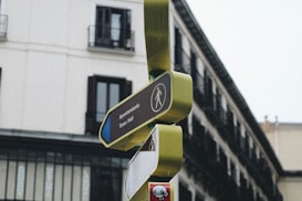 A street sign with a pedestrian symbol pointing towards the Town Hall, labeled 'Ayuntamiento' in both Spanish and English. The sign is mounted on a modern post with a background of a multi-story building with balconies.