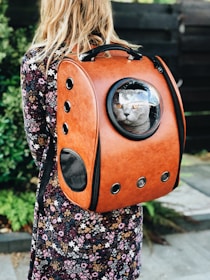 woman carrying pet carrier while standing near green plant