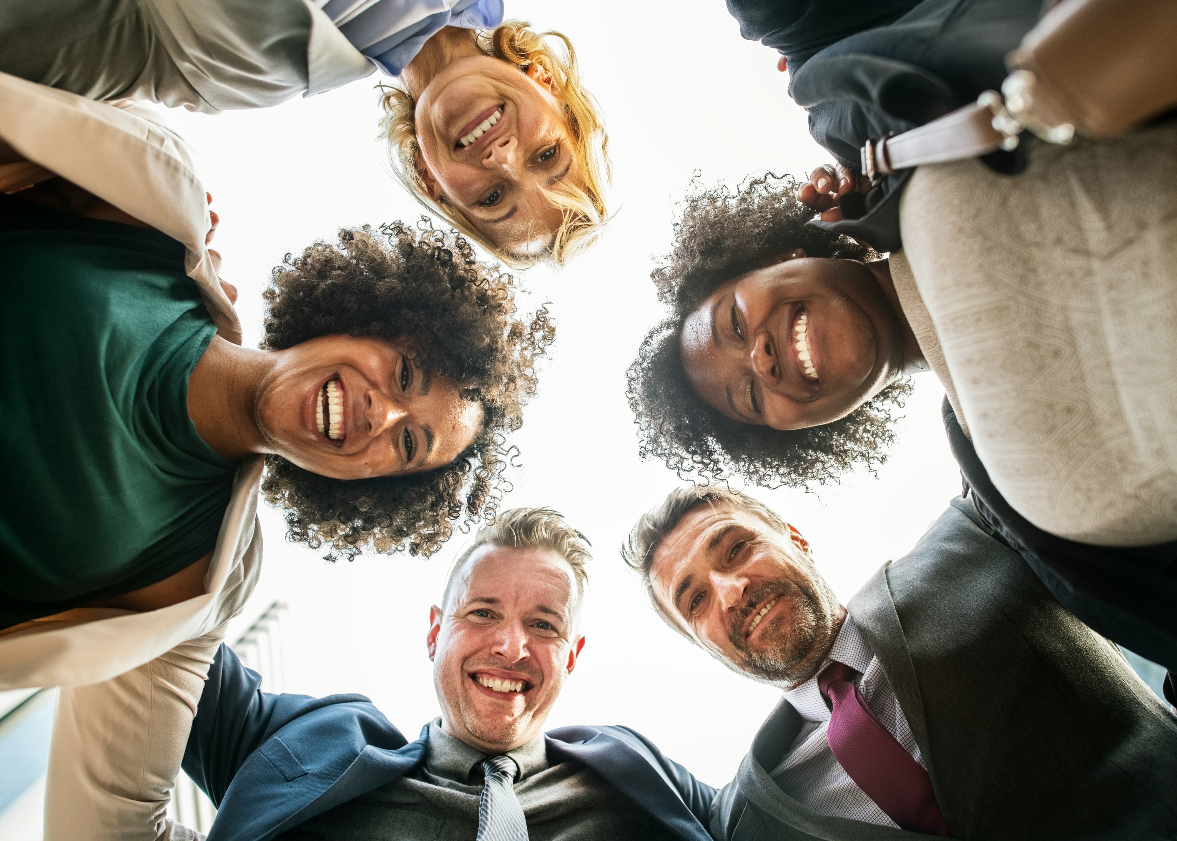 Group of people looking down on the camera arms over each other