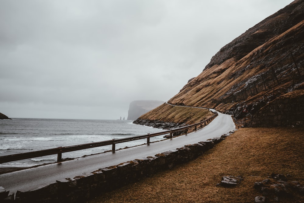 pavement road beside seashore under gray sky