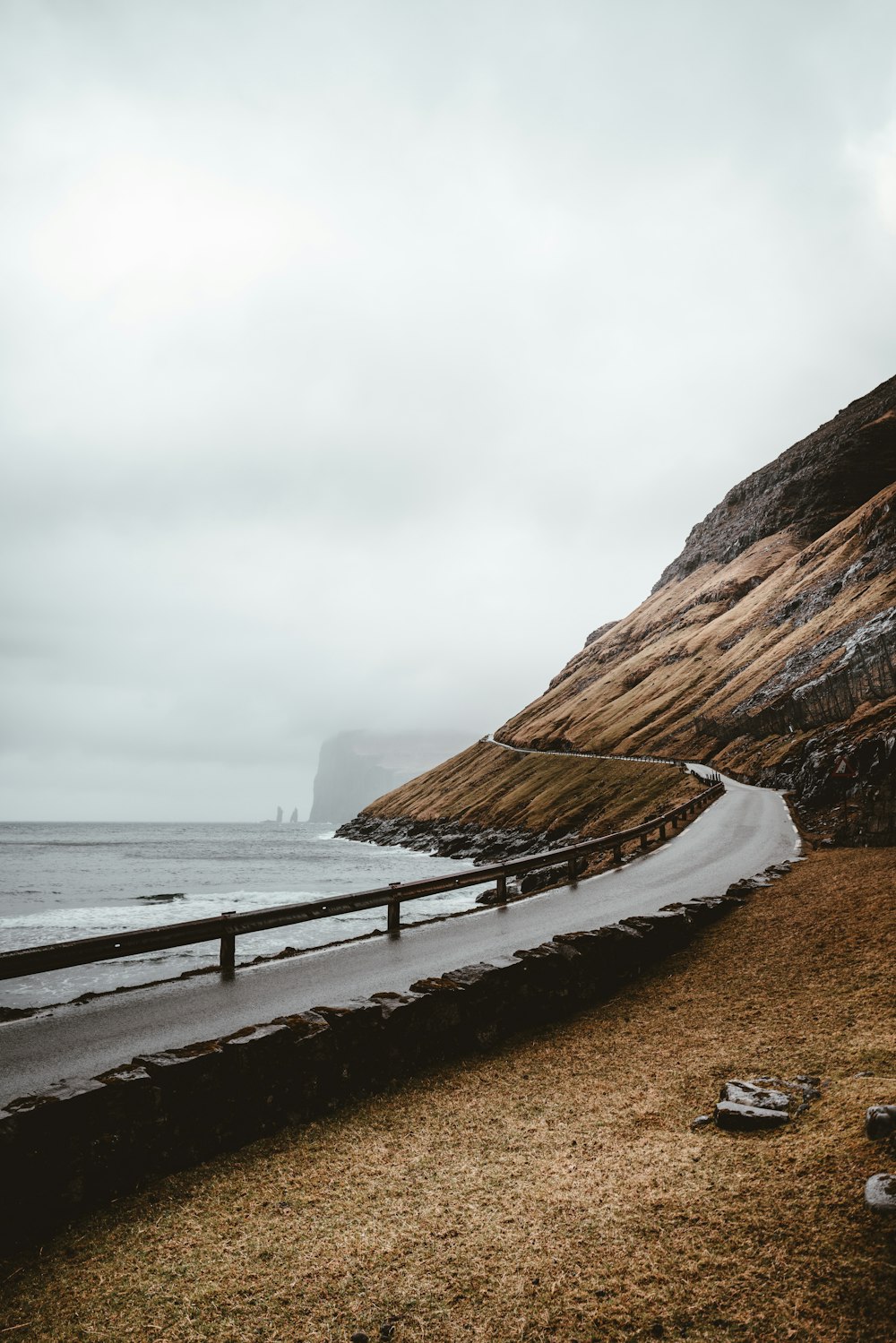 road between hill and body of water