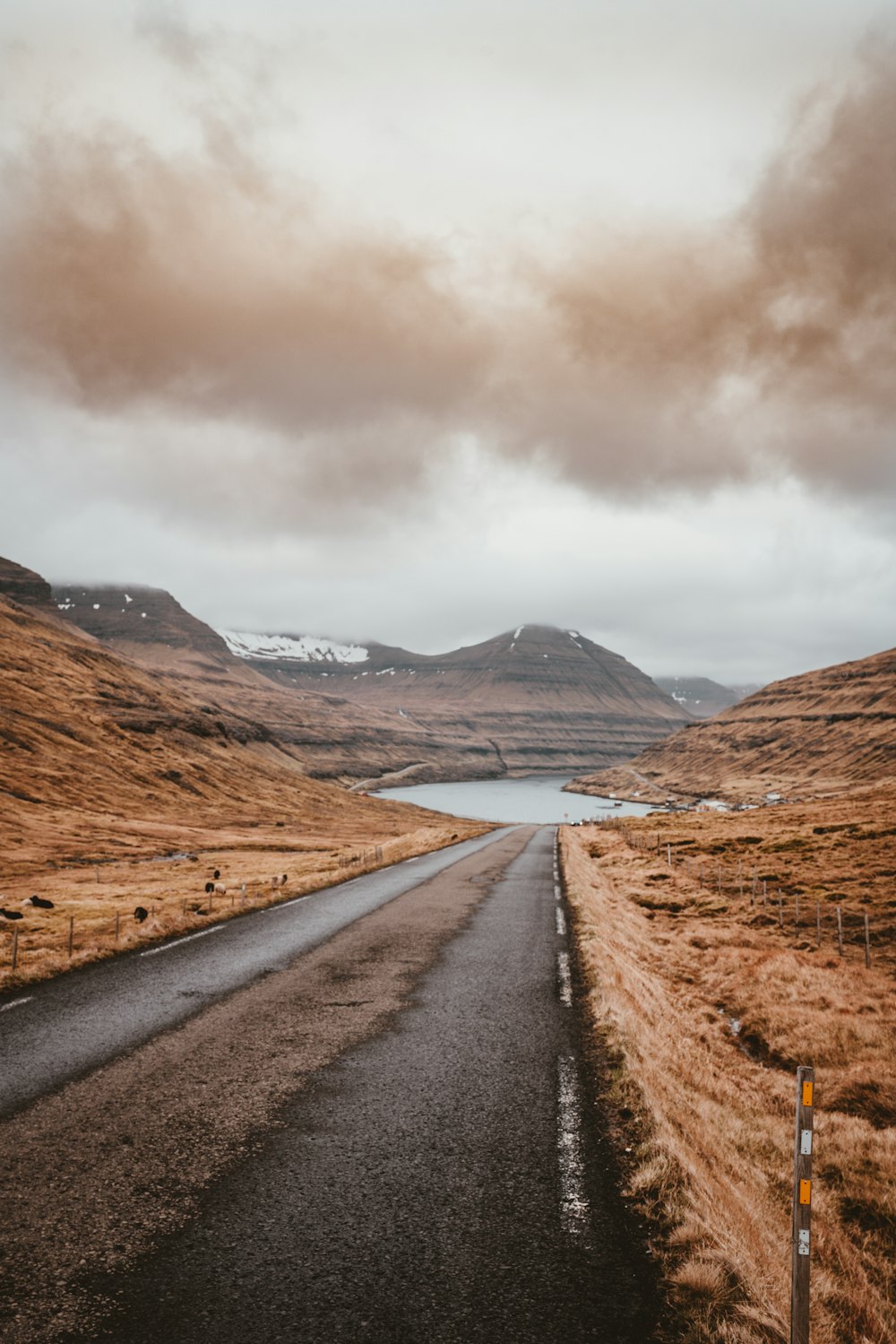 empty roadway near body of water and mountain during daytime