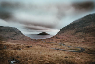 river surrounded by mountains under white cloudy sky at daytime