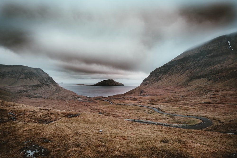 river surrounded by mountains under white cloudy sky at daytime