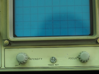 A close-up of a vintage oscilloscope with glowing green waveforms on its screen, reflecting years of use.