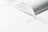 An open book with a white ribbon bookmark rests on a bright surface. The pages are crisp and the image is well-lit, conveying a sense of minimalism and cleanliness.