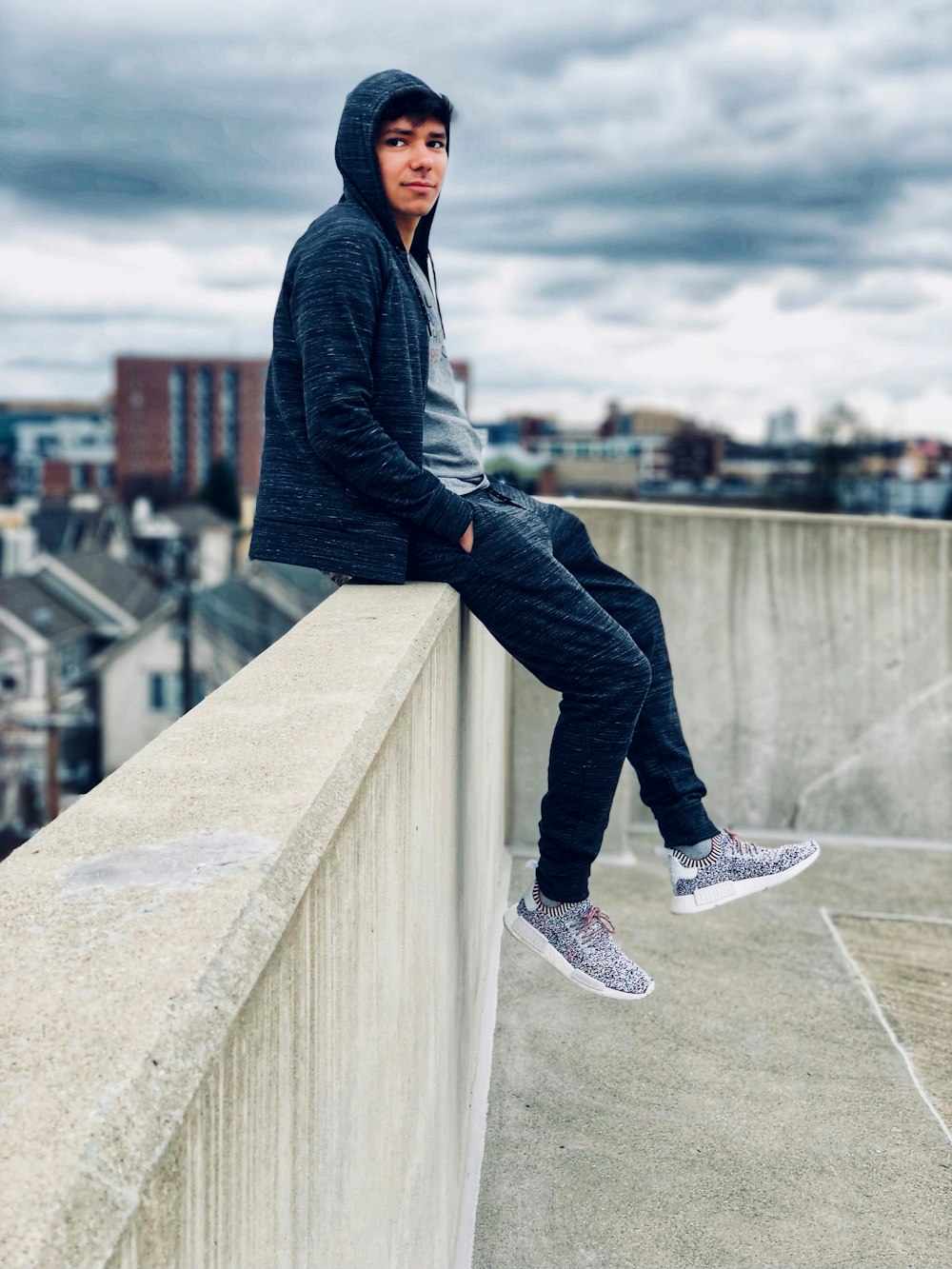 man sitting on railing while hands on pocket