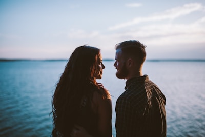 A serene moment of a couple gazing into each other's eyes by a lake.