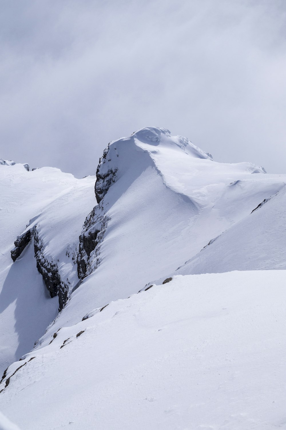 montanhas cobertas de neve sob o céu cinzento durante o dia