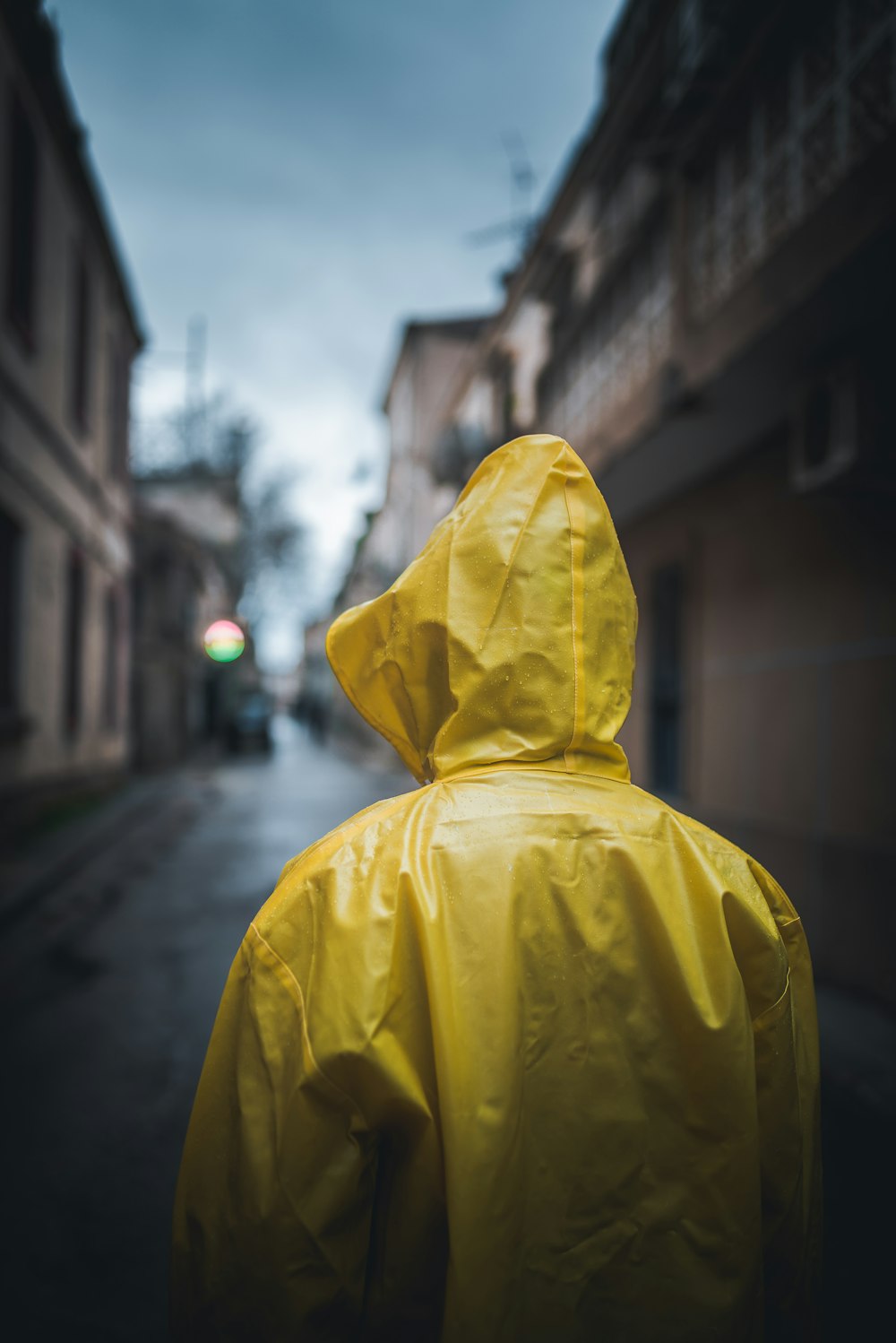 eine Person in einem gelben Regenmantel, die eine Straße entlang geht