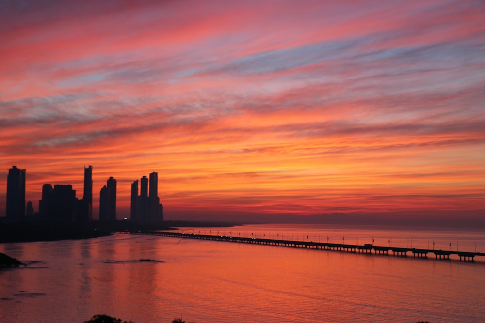 silhouette of buildings near body of water during dawn