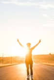 person raising both hands doing peace sign hand gesture on road during daytime