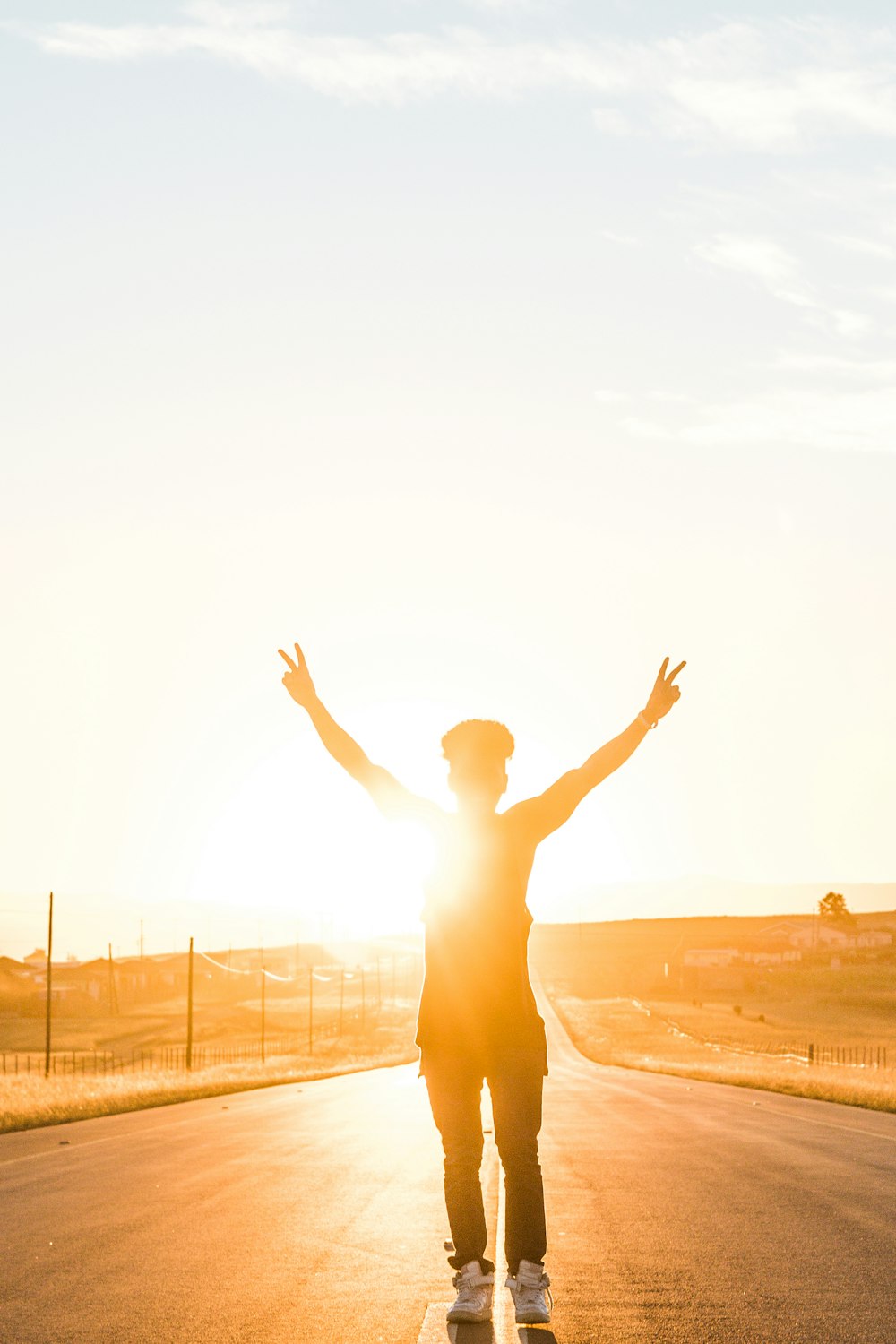 person raising both hands doing peace sign hand gesture on road during daytime