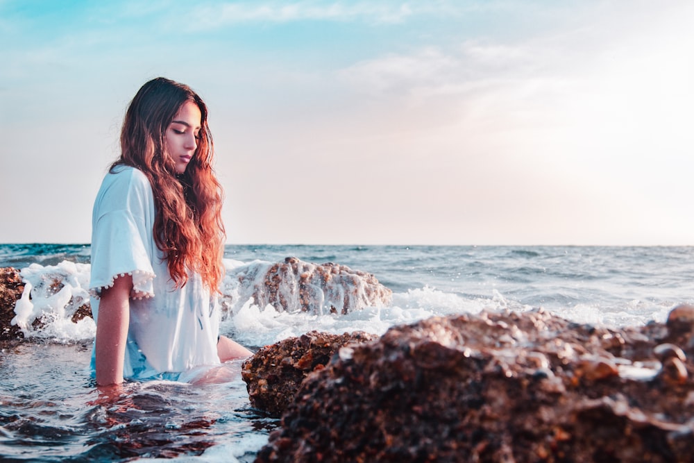 바위 해안에 앉아있는 여자