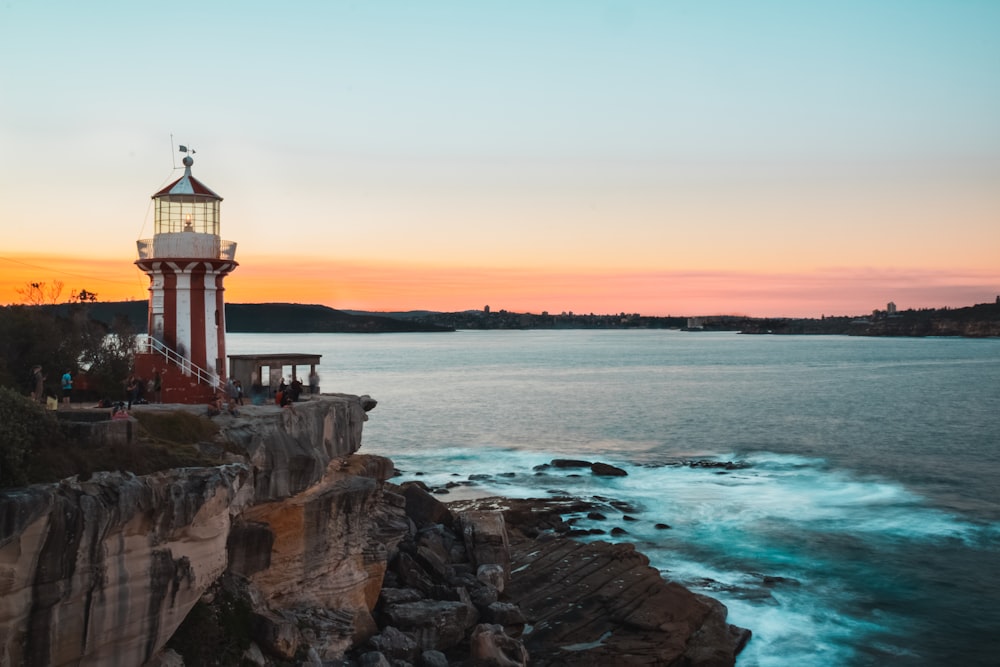 Un faro rosso e bianco seduto sulla cima di una scogliera vicino all'oceano