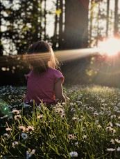 girl sitting on daisy flowerbed in forest