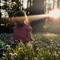 girl sitting on daisy flowerbed in forest