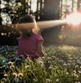 girl sitting on daisy flowerbed in forest