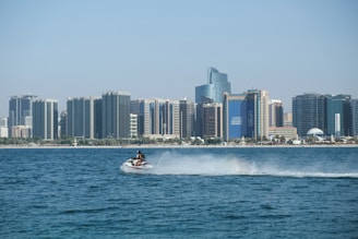 A close-up of jet skis speeding past iconic city landmarks on a clear day with blue skies.