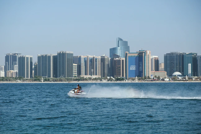 Sleek gold-accented jet ski gliding over dark waters at dusk with Dubai skyline in the background.