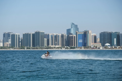 A close-up of jet skis speeding past iconic city landmarks on a clear day with blue skies.