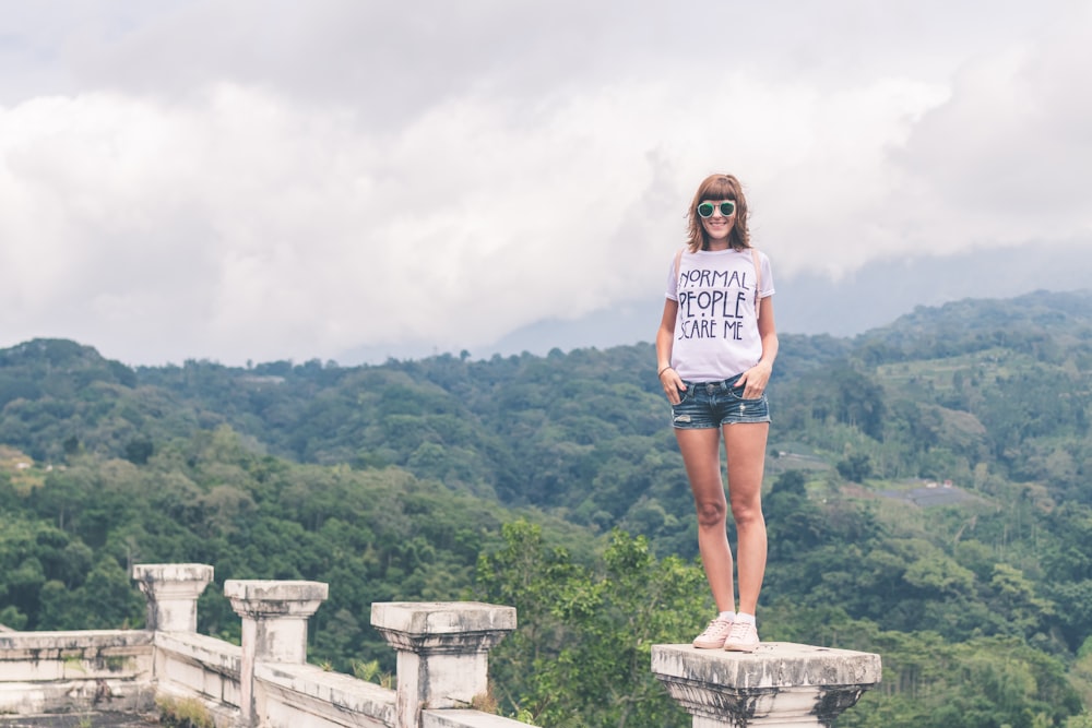 woman standing on concrete pillar