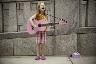 girl playing guitar near wall
