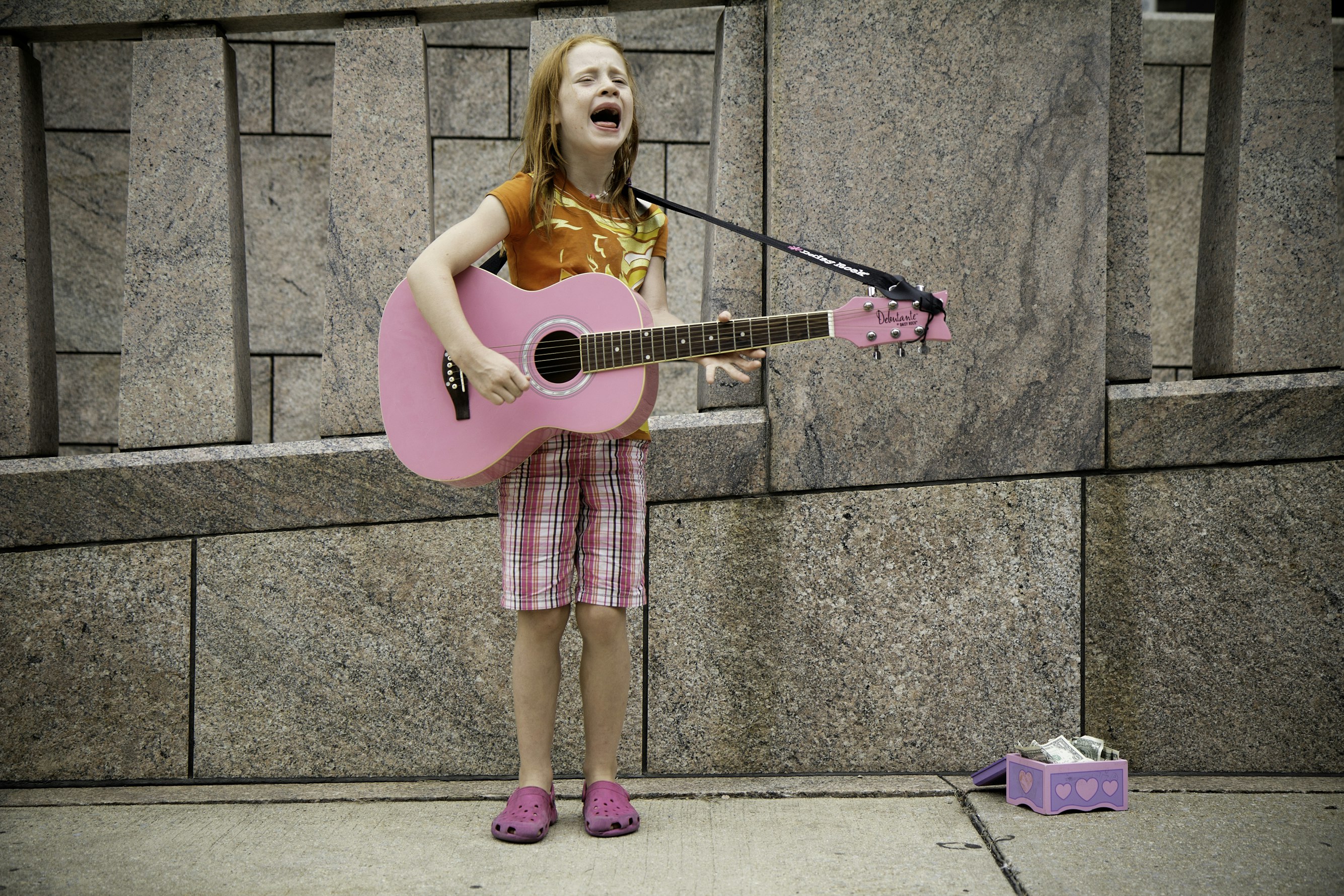 Girl playing guitar near wall. Photo by Felix Koutchinski