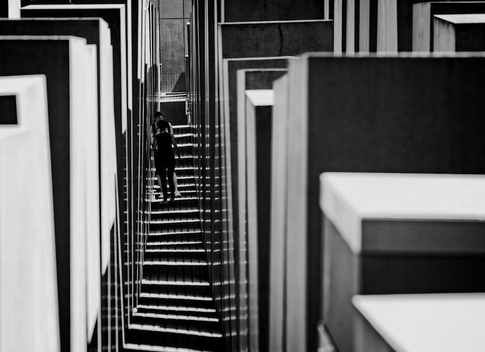 a black and white photo of a person walking down a set of stairs