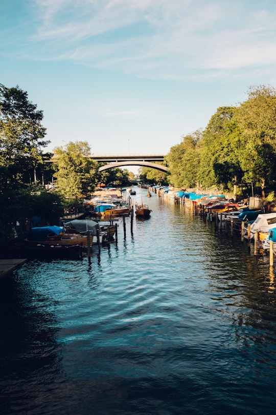 boats on canal near bridge and trees during daytime in Långholmen Sweden