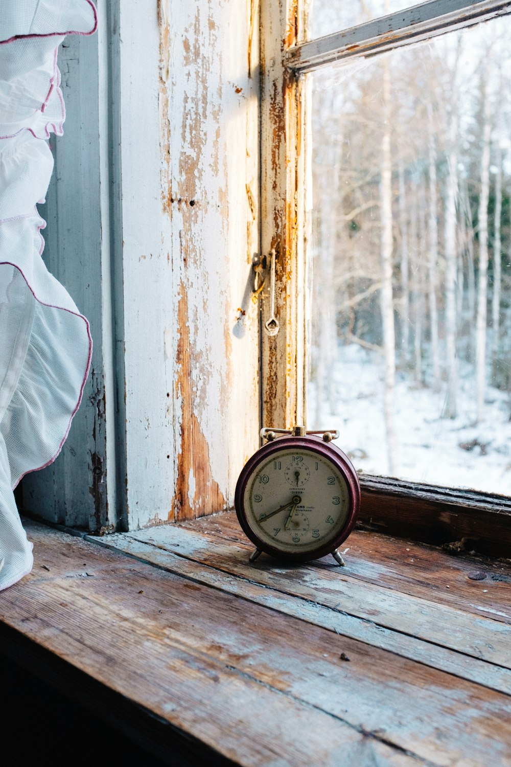 photo of red analog alarm clock beside window