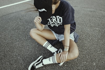 woman wearing black and white crew-neck shirt and gray shorts on gray concrete ground