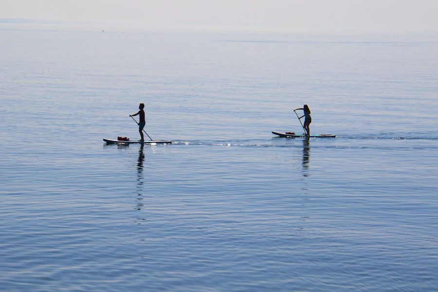 Beginner paddleboarders standing on boards on a calm, flat body of water