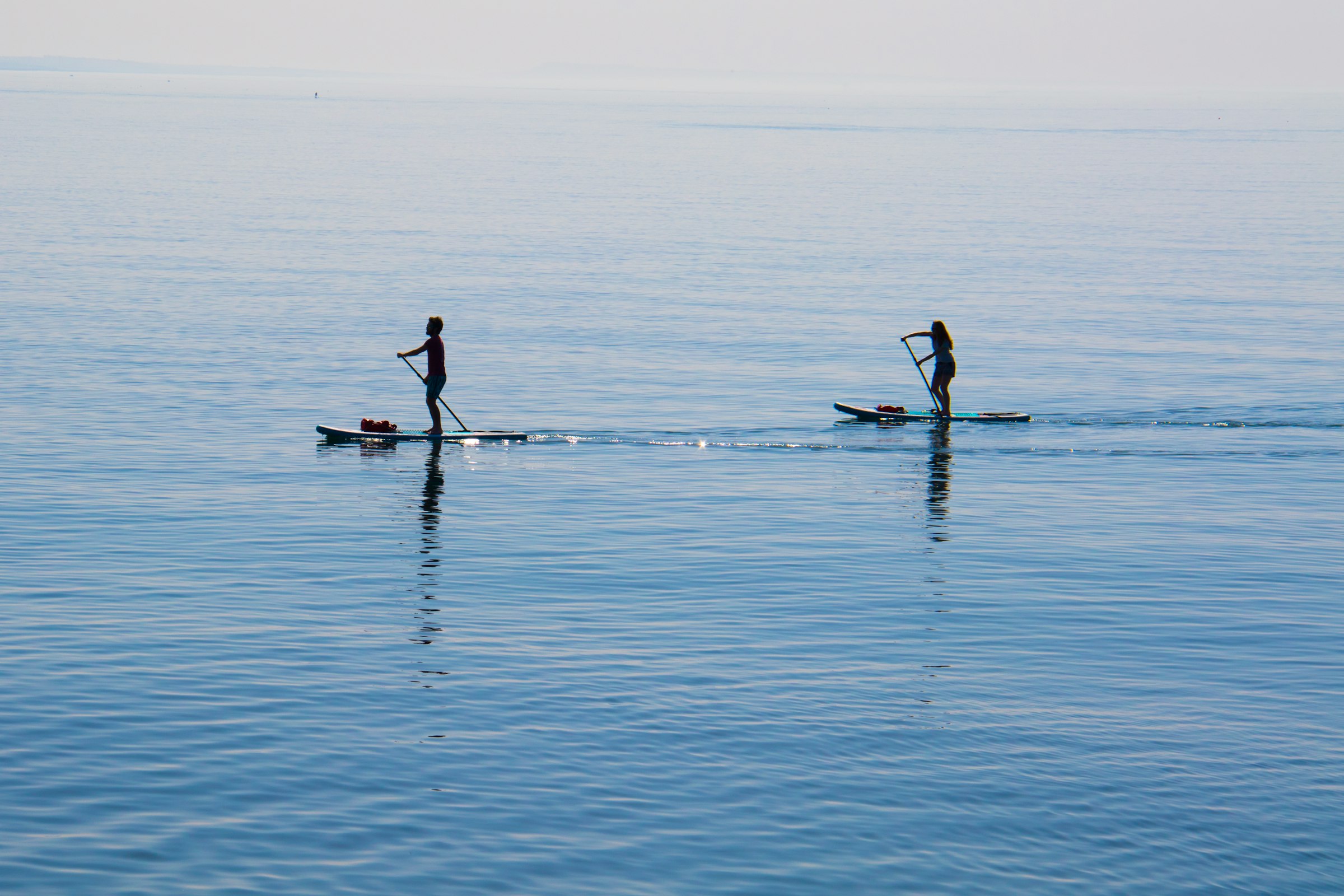 people ridding paddleboard on body of water