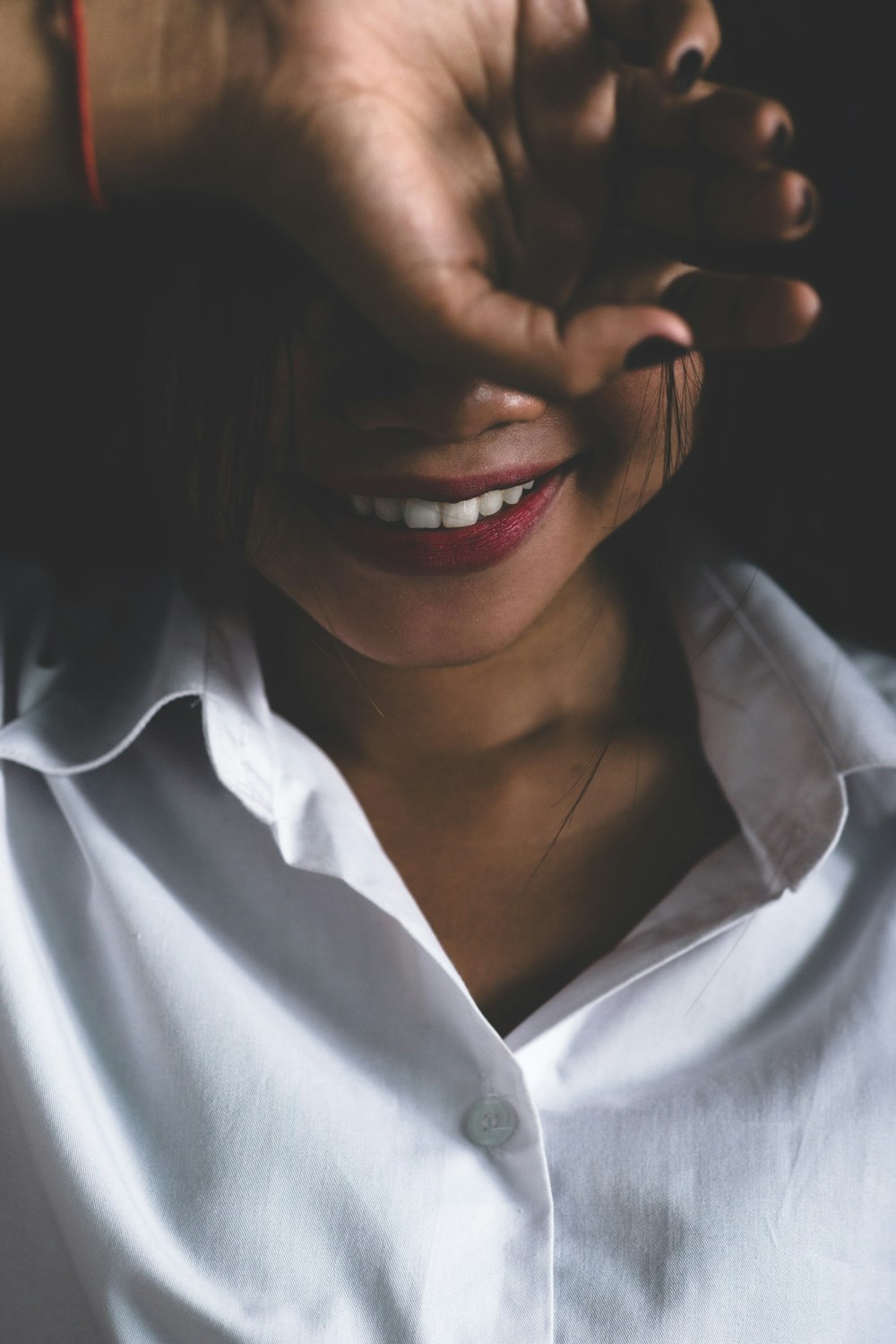 smiling woman covering her eyes on her hand