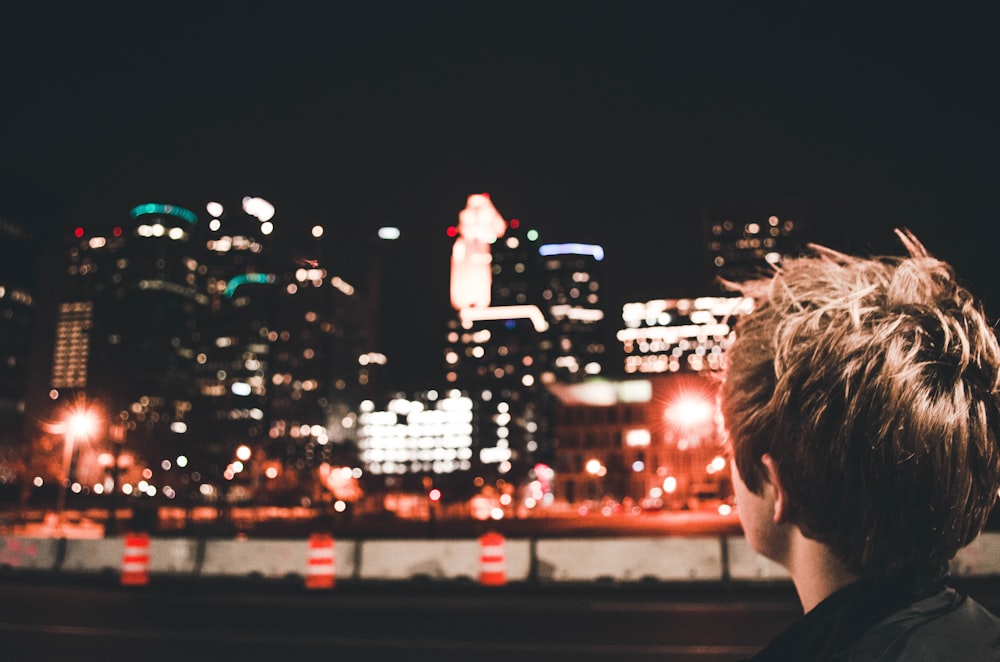 man standing near high rise building during night time