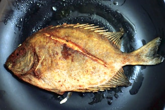 Freshly cooked fish fry with a crispy, golden crust on a rustic wooden board.