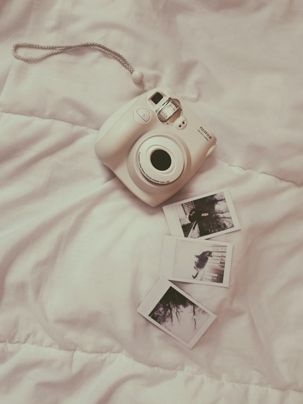 weiße Fujifilm Sofortbildkamera auf weißer Bettdecke