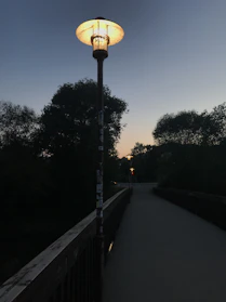 A warm solar garden pathway light glowing softly along a stone walkway at dusk