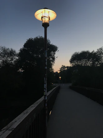 A beautifully lit park pathway at dusk featuring sleek solar garden lights casting a warm glow.