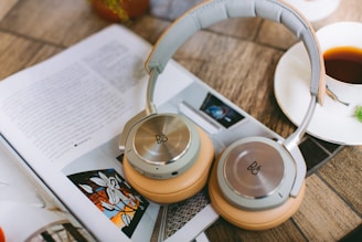 gray and yellow on-ear headphones beside white ceramic cup