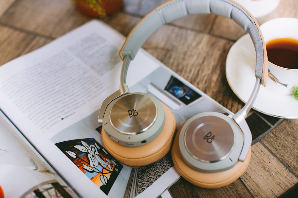 Auriculares on-ear grises y amarillos junto a una copa de cerámica blanca