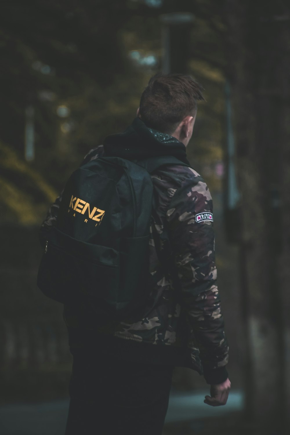 homme portant une veste de camouflage et un sac à dos