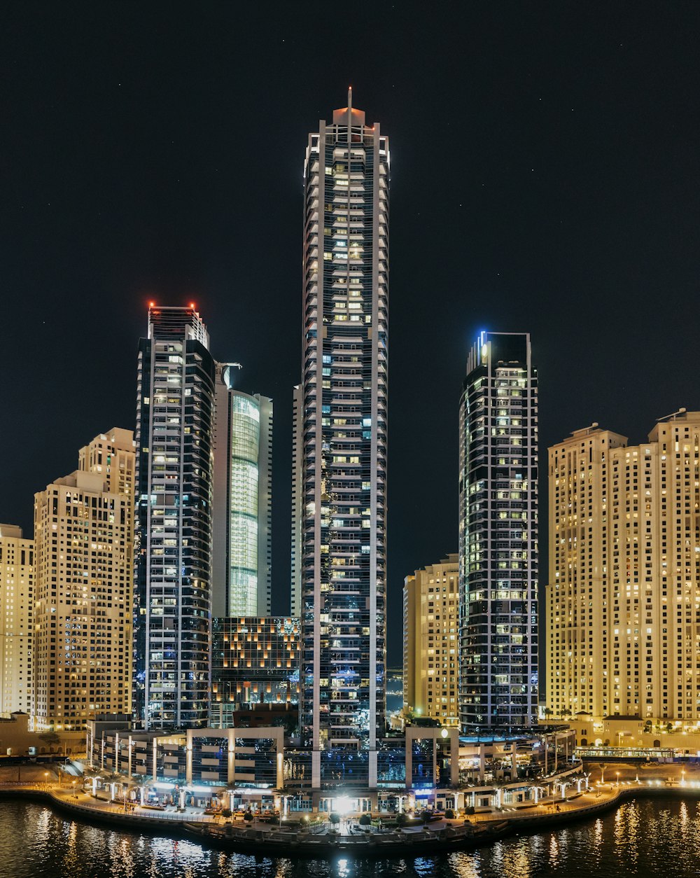 Tres rascacielos iluminados cerca de un cuerpo de agua