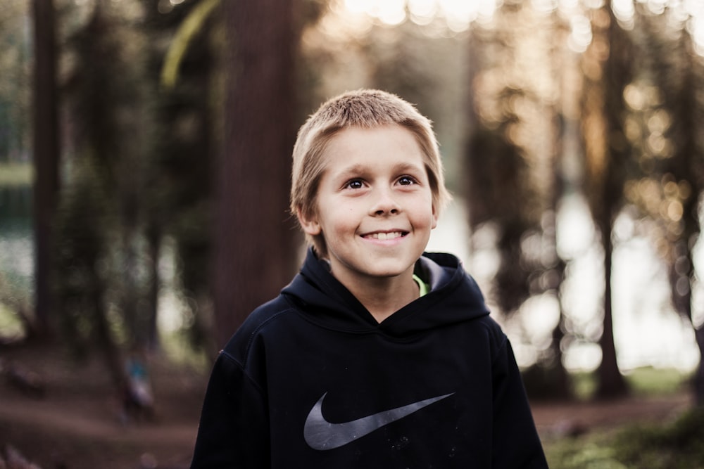 close-up photography of boy in black Nike pullover smiling