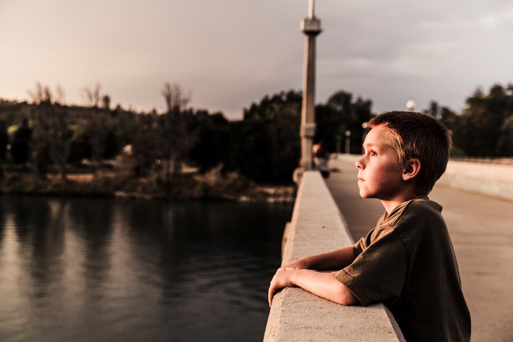 水域近くの橋の少年のセレクティブフォーカス写真