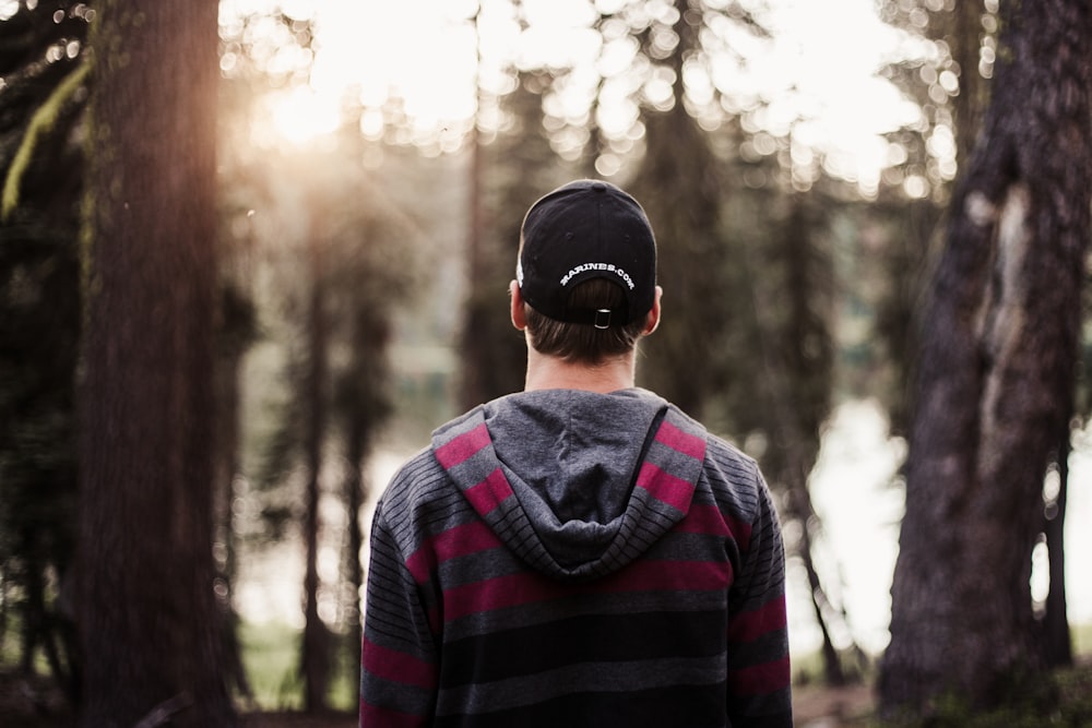 photo de mise au point sélective d’un homme debout devant des arbres pendant la journée