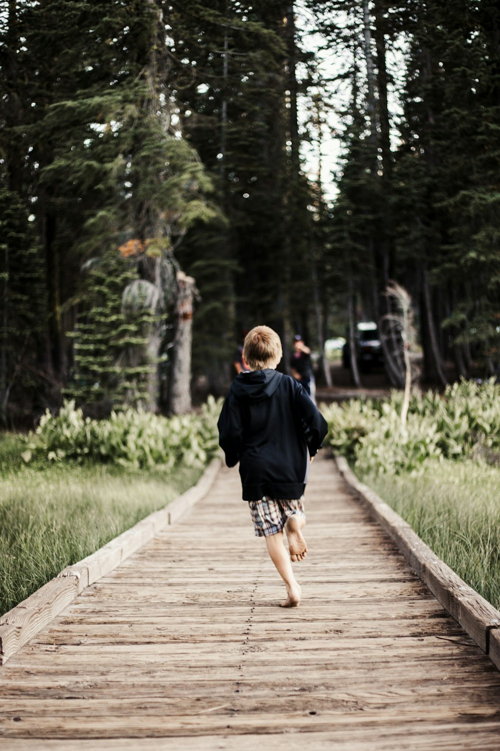 Enfant en bas âge courant sur un sentier en bois brun
